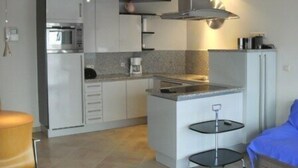 A compact kitchen with white cabinets, a built-in microwave, a coffee maker, and a small island with a sink. - Knokke-Zoute - Exclusive Sun and Sea Village Near Bruges (Knokke-Heist)