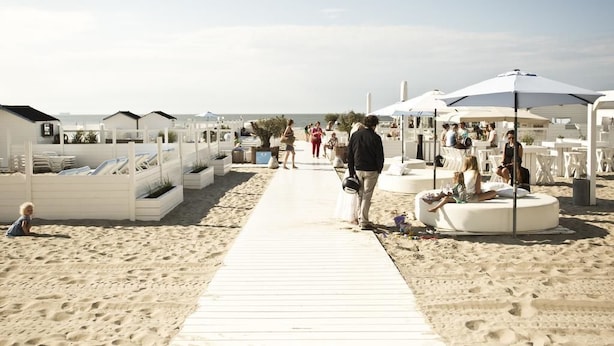 A beachside resort with a wooden walkway, white lounge chairs, and umbrellas. - Knokke-Zoute - Exclusive Sun and Sea Village Near Bruges (Knokke-Heist)
