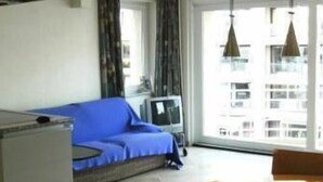 A modern living room with a sofa, a dining table with chairs, and a television. - Knokke-Zoute - Exclusive Sun and Sea Village Near Bruges (Knokke-Heist)