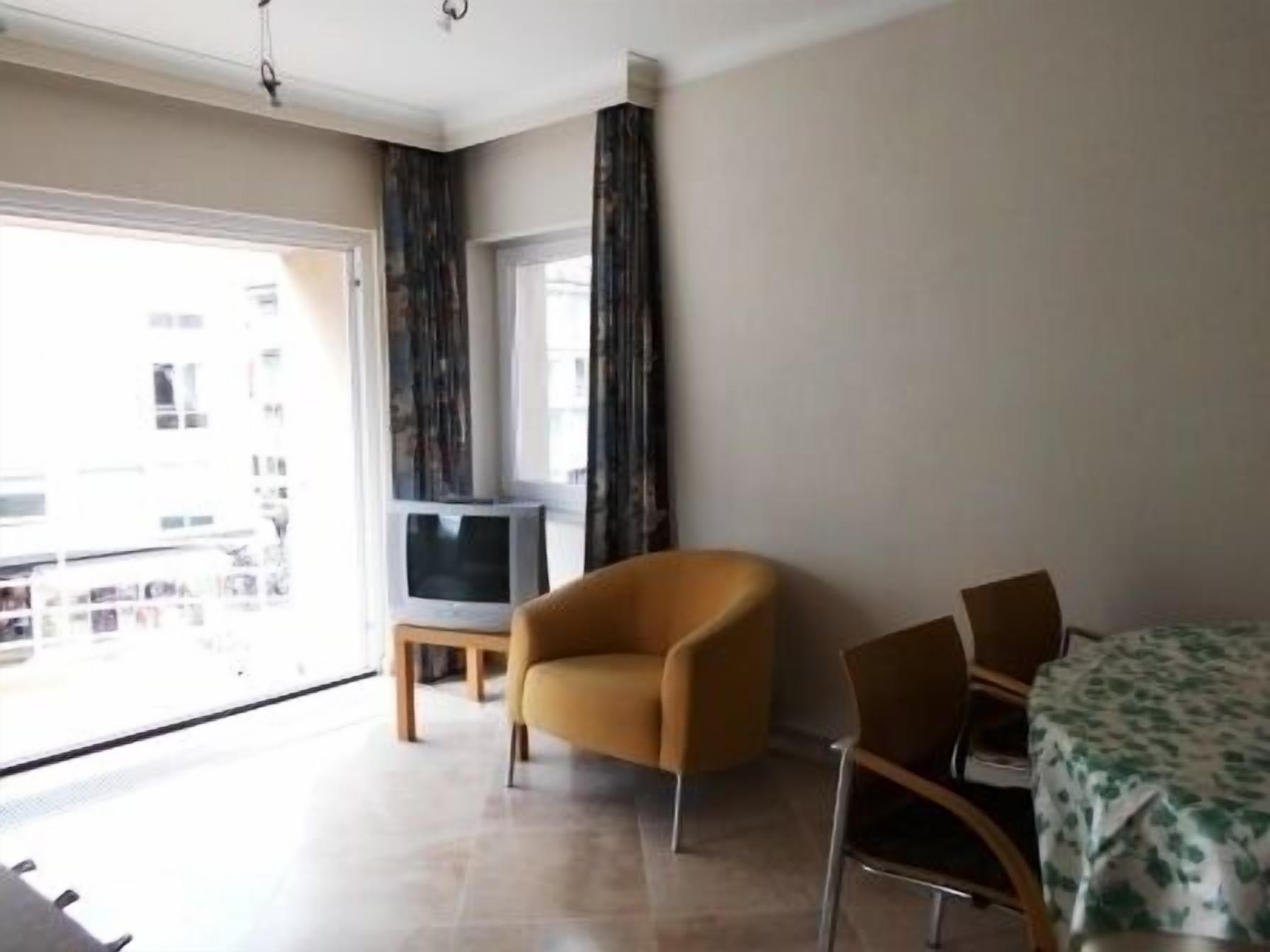 A room with a large window, a television, a sofa, and a dining table.