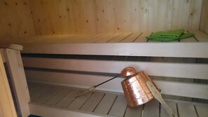 Relax in a serene sauna with a bucket suspended from the ceiling and a towel at hand.
