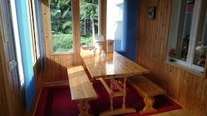 Enjoy meals around a large table with benches in a room with a view of the surrounding greenery.