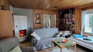 Interior acogedor de una cabaña con un sofá, una mesita, una estantería y una cama.