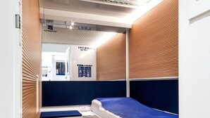 Habitación pequeña con una litera, paredes de paneles de madera, techo con diseño de cuadrícula y un escritorio con computadora.
