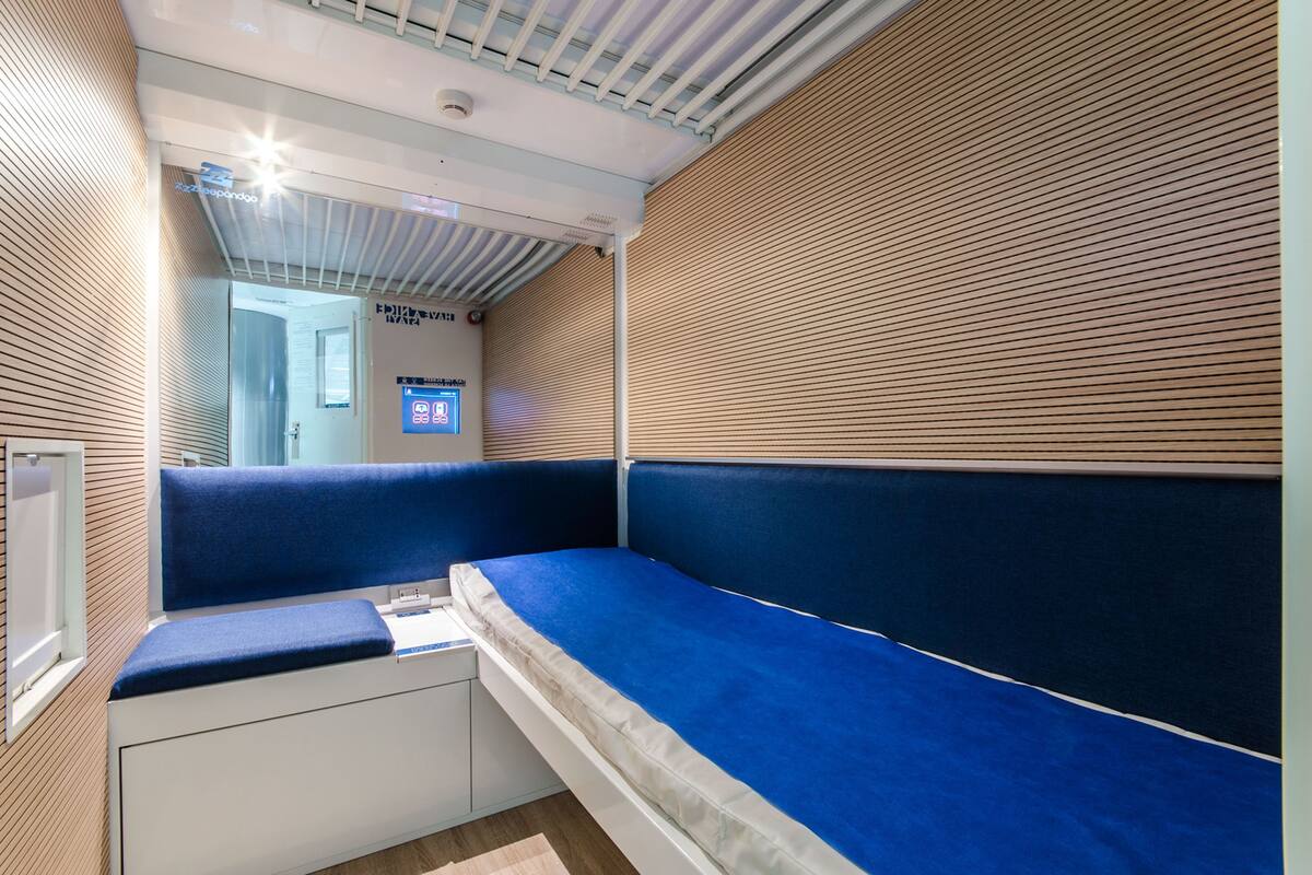 A modern hotel room with a built-in bench, a small desk, and a window.