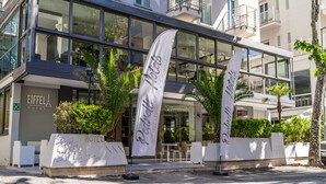 Un hôtel moderne doté de grandes baies vitrées, d’une terrasse et de palmiers.