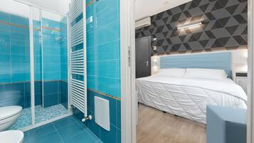 Un baño moderno con azulejos azules, una cabina de ducha de vidrio y un inodoro blanco.