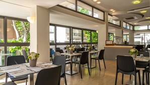 Un restaurant moderne avec de hauts plafonds, de grandes fenêtres et un aménagement épuré et bien organisé.