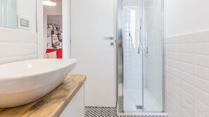 Une salle de bain avec un lavabo blanc, une douche en verre et un sol carrelé.