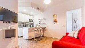 Un appartement moderne doté d’une cuisine, d’un coin repas et d’un canapé rouge.