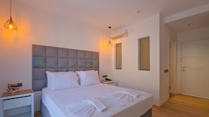 A modern hotel room with a large bed, bedside tables, a headboard with artwork, and a wardrobe.