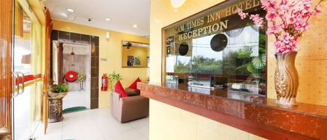 A hotel reception area with a reception desk, a sofa, and a vase with flowers.