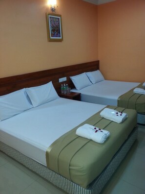 A hotel room with two beds, a nightstand with toiletries, and a framed picture on the wall.