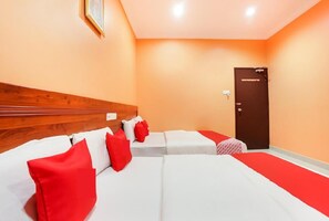 A hotel room with a wooden headboard, two beds with red and white bedding, a red carpet, and a door. - Bercam Times Inn Hotel (Ipoh)