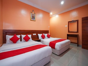 Habitación de hotel con dos camas, cada una con ropa blanca y detalles rojos, un cabecero de madera, una mesita de noche pequeña, un espejo y un cuadro en la pared.