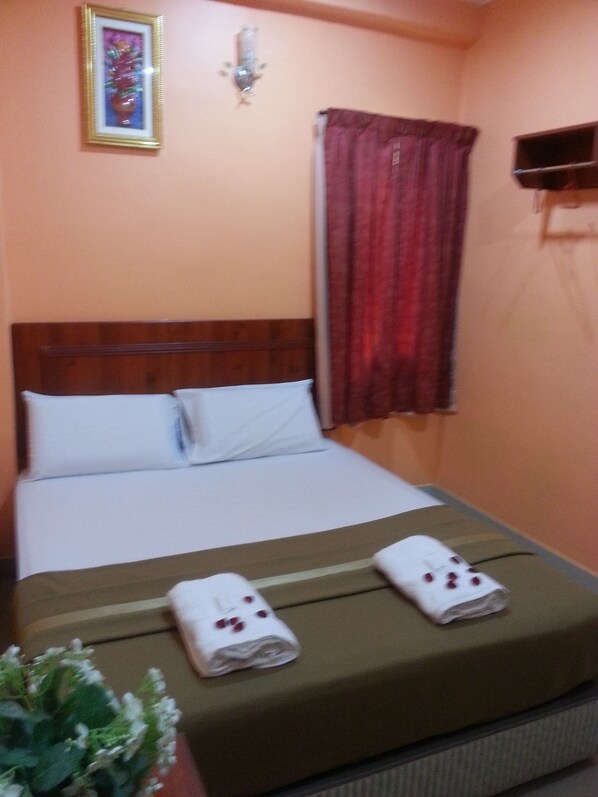 A hotel room with a bed, pillows, a nightstand, a lamp, a window with curtains, and a framed picture on the wall. - Bercam Times Inn Hotel (Ipoh)