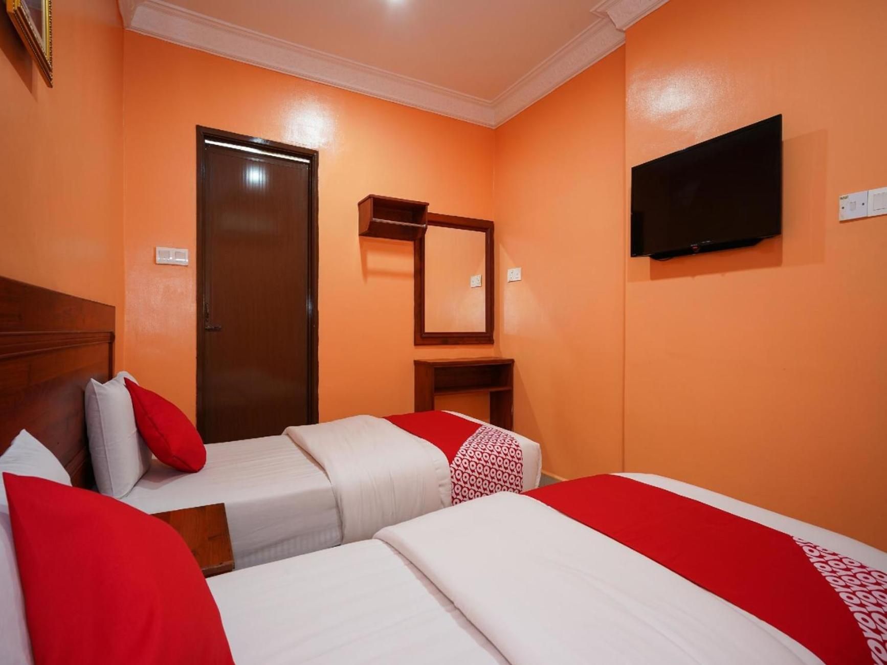 A hotel room with two beds, a television, a door, and a mirror.