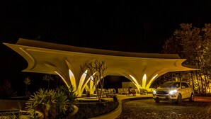 A modern building with a unique architectural design, featuring a curved roof structure and a paved entrance area. - Java Rain Resorts (Chikkamagaluru)