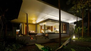 A modern house with a large glass facade, a dining area with a table and chairs, and a staircase leading to the upper level. - Java Rain Resorts (Chikkamagaluru)
