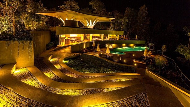 A modern, illuminated outdoor area with a pool, seating, and a covered structure. - Java Rain Resorts (Chikkamagaluru)