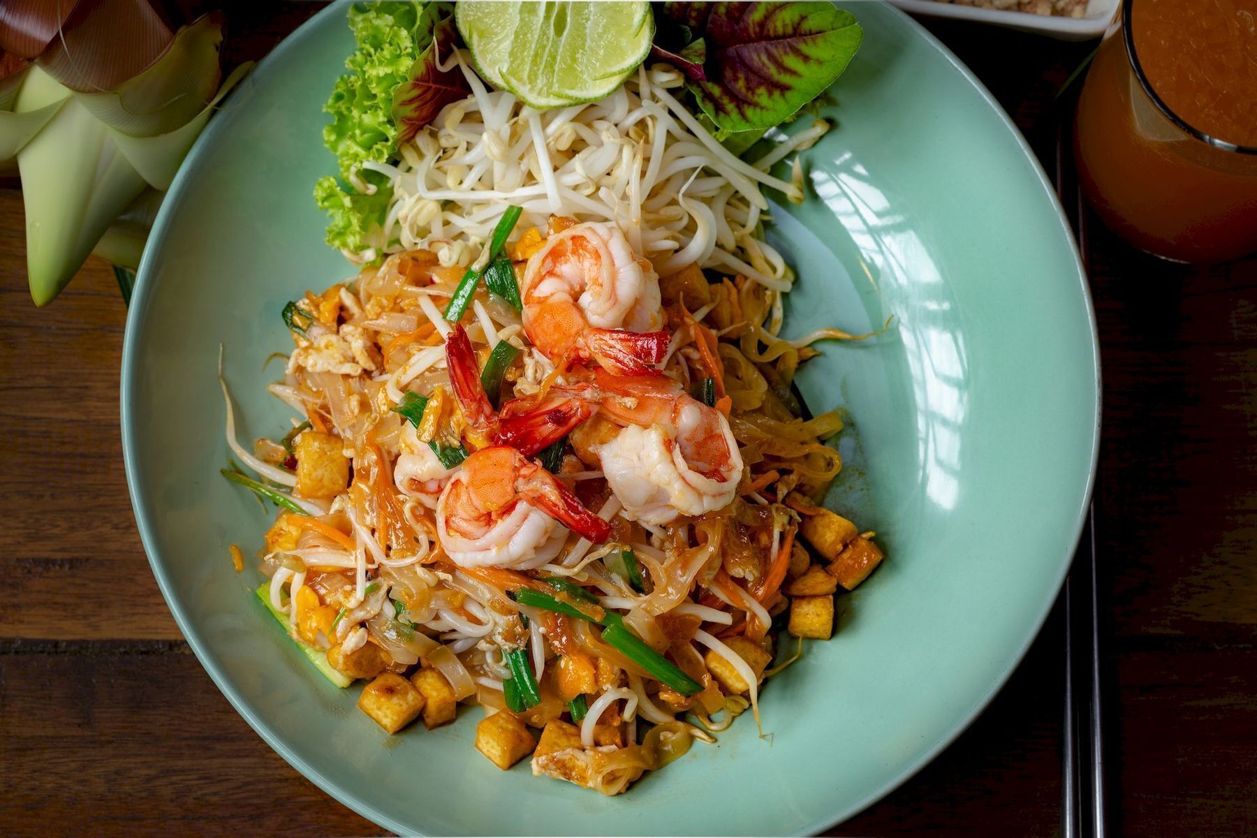 Une assiette de Pad Thaï aux crevettes, aux pousses de soja et aux légumes.