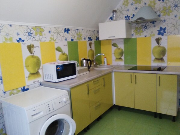 A compact kitchen with a microwave, sink, and washing machine.