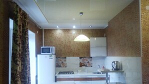 A compact kitchen with a microwave, stove, sink, and a washing machine. - Apartments Galactika (Uralsk)