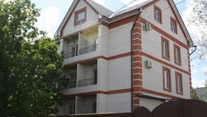 A multi-story building with a brick facade, multiple balconies, and a gated entrance. - Apartments Galactika (Uralsk)
