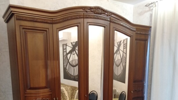 A wooden wardrobe with mirrored doors and a decorative top. - Apartments Galactika (Uralsk)