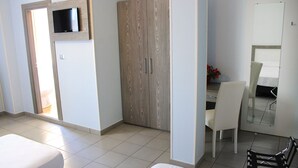 A hotel room with a bed, a desk with a chair, a wardrobe, and a television on the wall. - Hotel Savoia (Poggio Rusco)