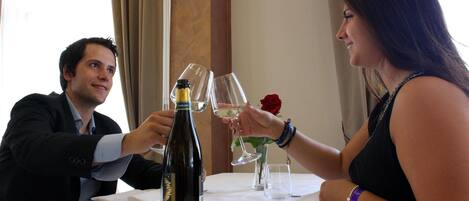 A dining table with a bottle of wine, a glass, and a rose.
