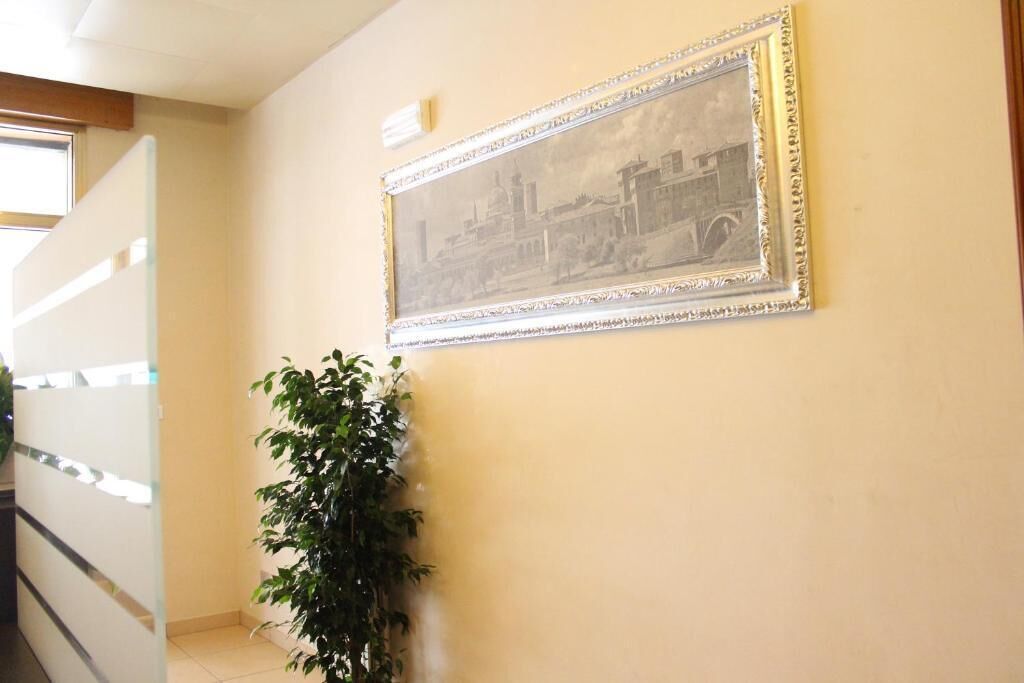 A hallway with a framed picture on the wall, a staircase, and a potted plant.