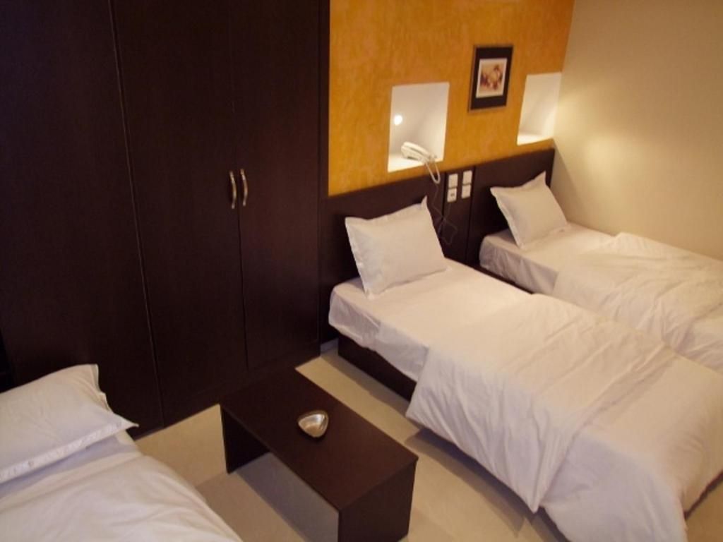 Une chambre d’hôtel avec deux lits simples, une tête de lit en bois, des lampes de chevet, une petite table et un téléphone.