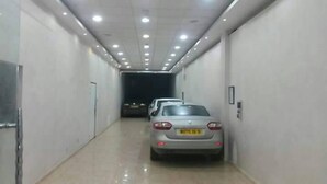 A narrow, well-lit hallway with two parked cars and a door at the end. - Hotel Ikram (Algiers)