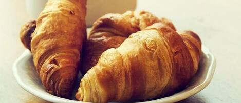 Ein Teller mit Croissants und eine Tasse Kaffee auf einem Holztisch.