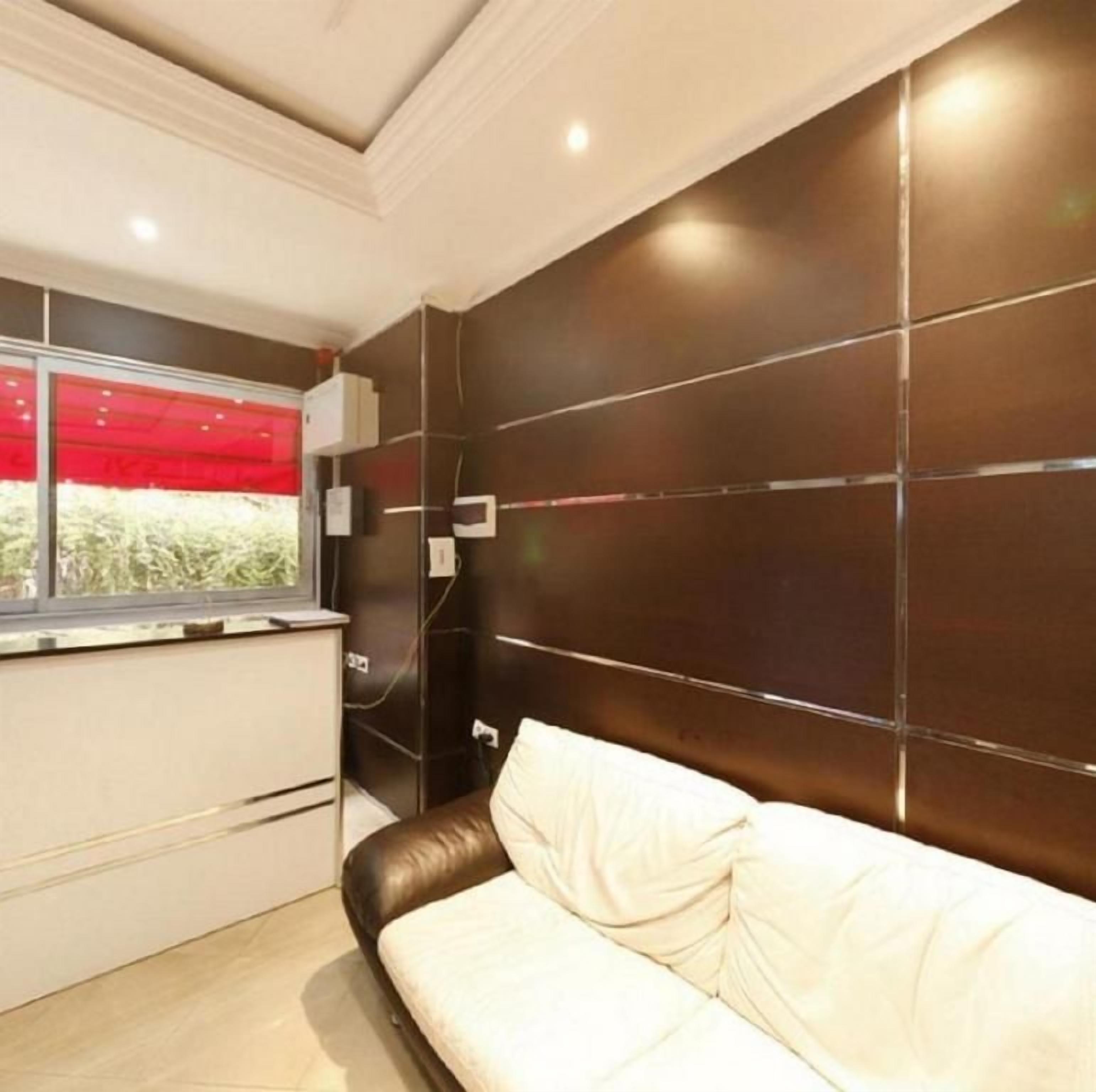 Una habitación moderna con un panel de pared oscuro, un sofá blanco y un ventanal con un toldo rojo.