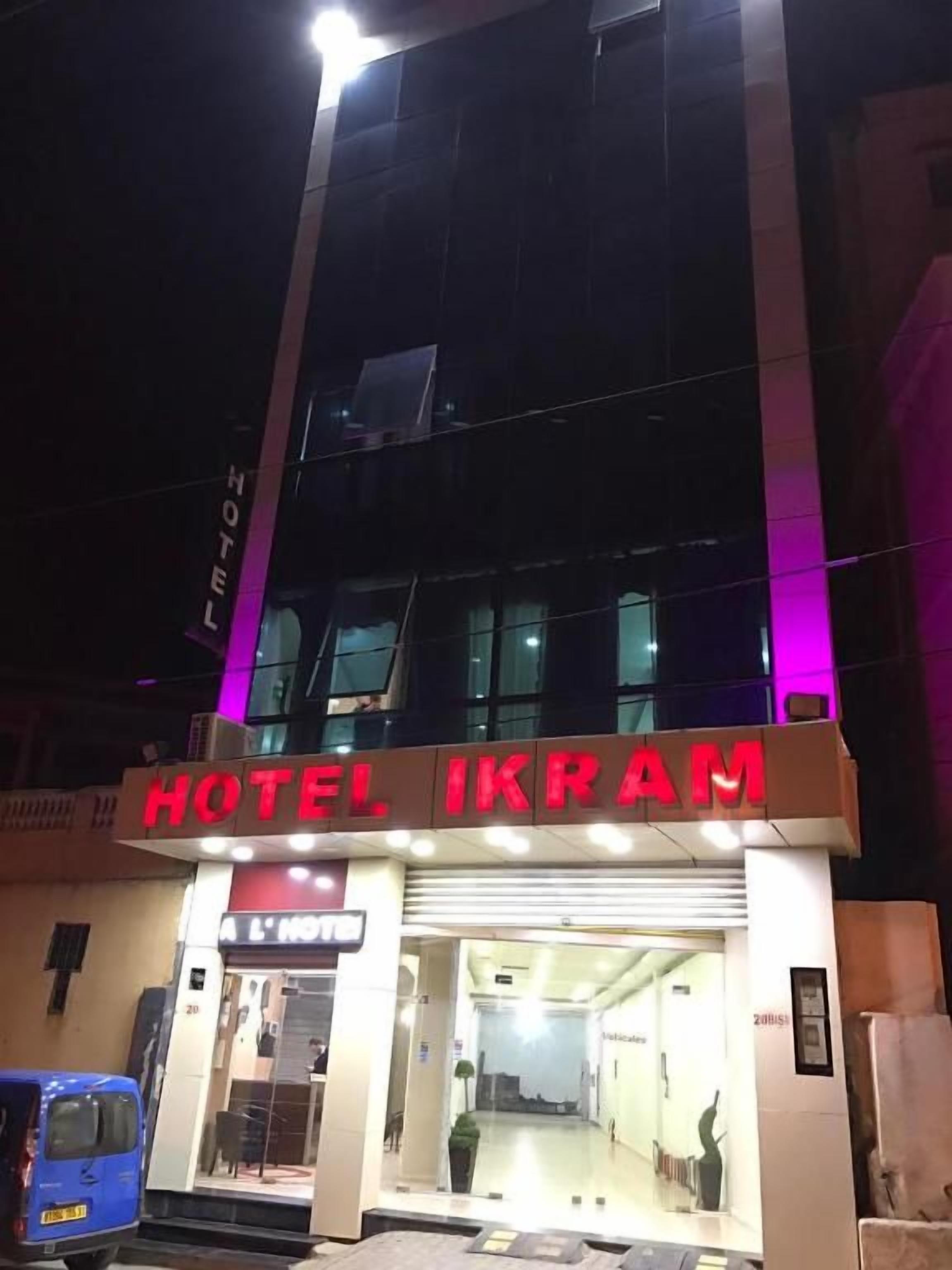 A hotel entrance with a sign reading 'HOTEL IKRAM' and a blue vehicle parked outside.