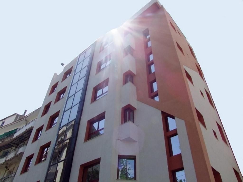 Un edificio de varios pisos con un diseño arquitectónico moderno, que combina elementos de fachada de vidrio y superficies sólidas.