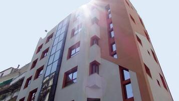 Un edificio de varios pisos con un diseño arquitectónico moderno, que combina elementos de fachada de vidrio y superficies sólidas.