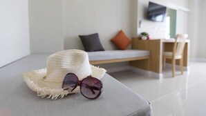 Un salon moderne avec un canapé, une petite table et un téléviseur fixé au mur.