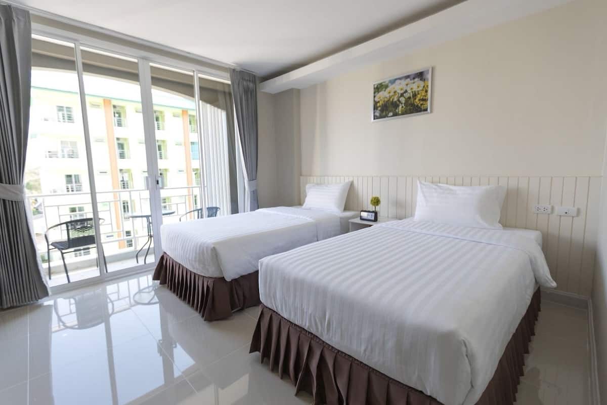 A hotel room with two beds, a balcony with a chair, and a painting on the wall.