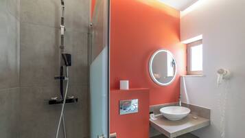 A modern bathroom with a glass shower enclosure, a white sink, and a mirror.