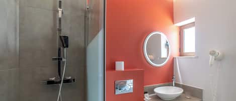 A modern bathroom with a glass shower enclosure, a white sink, and a mirror.