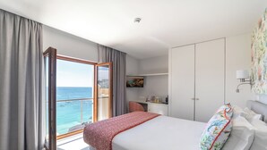 Une chambre d’hôtel avec un lit, un bureau et une vue sur la mer.