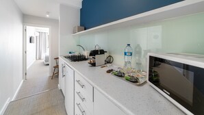 Une cuisine moderne avec des meubles blancs, un four à micro-ondes et une machine à café posés sur le plan de travail.
