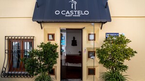 Un bâtiment sur lequel on peut lire l’inscription « O CASTELO GUEST HOUSE » et dont la porte donne accès à un espace intérieur.