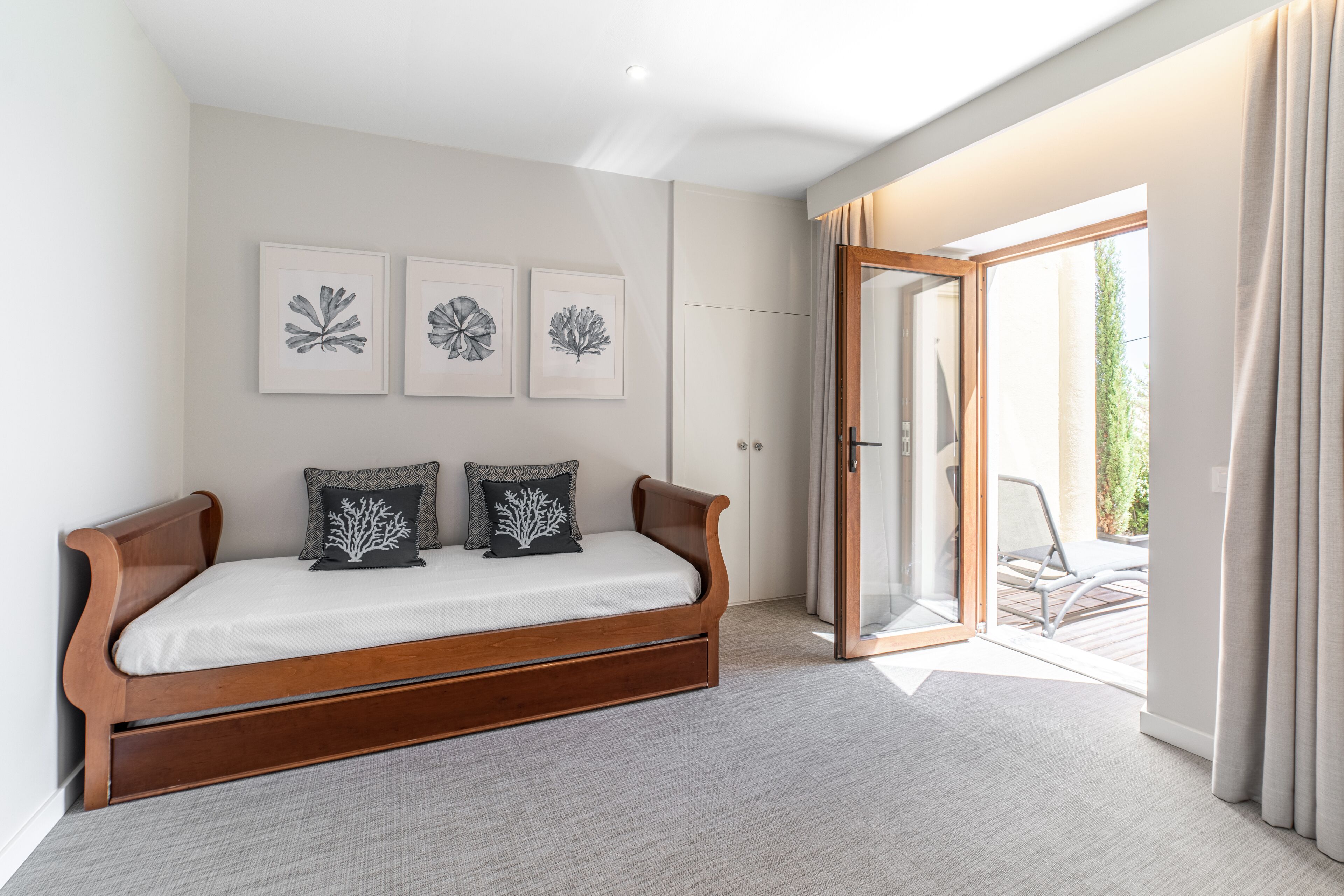A bedroom with a wooden bed, a large window, and a sliding glass door leading to an outdoor area.
