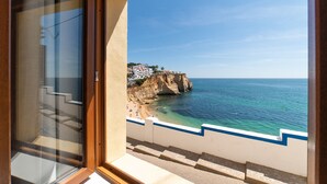 Une vue sur la côte depuis un balcon, avec un ciel dégagé, une plage et une falaise.