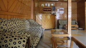 Un interior de madera con un sofá estampado, un mostrador de recepción y un sillón con diseño.