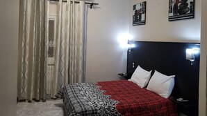 Une chambre à coucher avec un lit, des rideaux, un appareil de climatisation et des lampes fixées au mur.